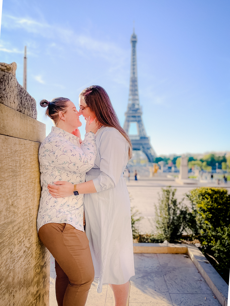 two queer women travelers kissing in front of eiffel tower