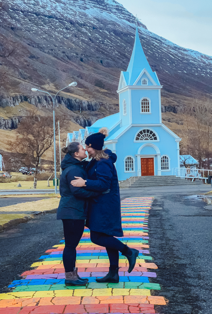 two queer women travelers kissing on rainbow bridge