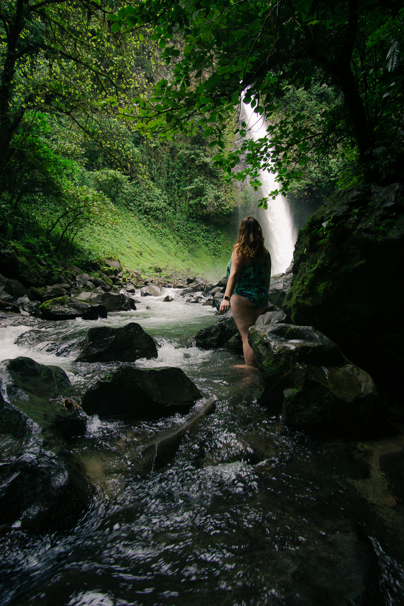 Woman standing in river near La Fortuna Waterfall