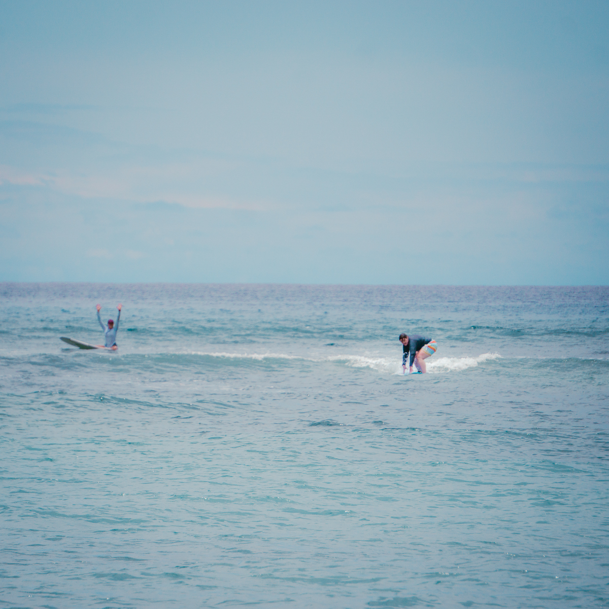Woman standing on surfboard during Maui Surfer Girls lesson