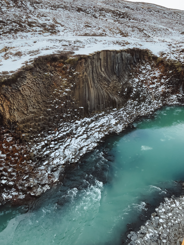 Snowy basalt columns and teal blue water at Stuðlagil Canyon