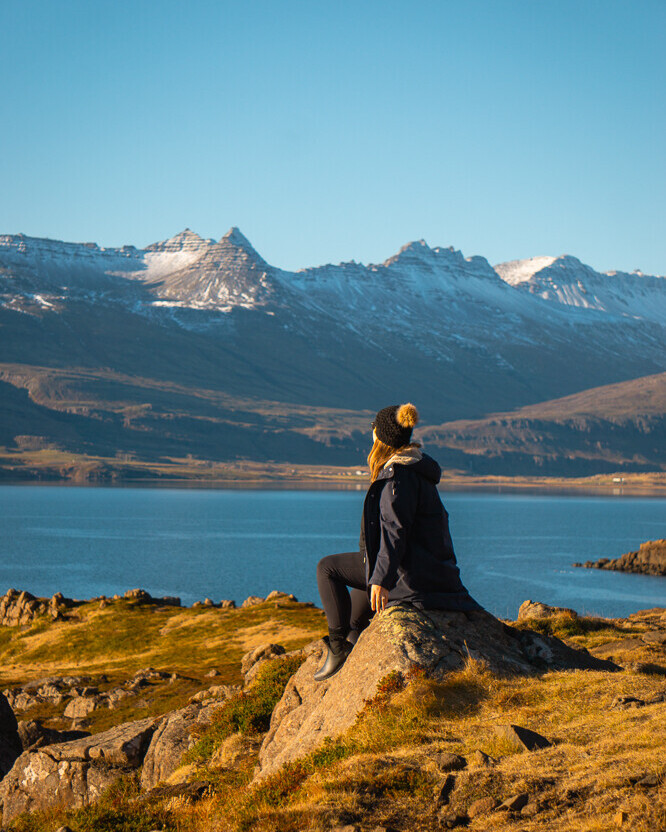 Woman sitting on rock in front of mountains of east fjords Iceland