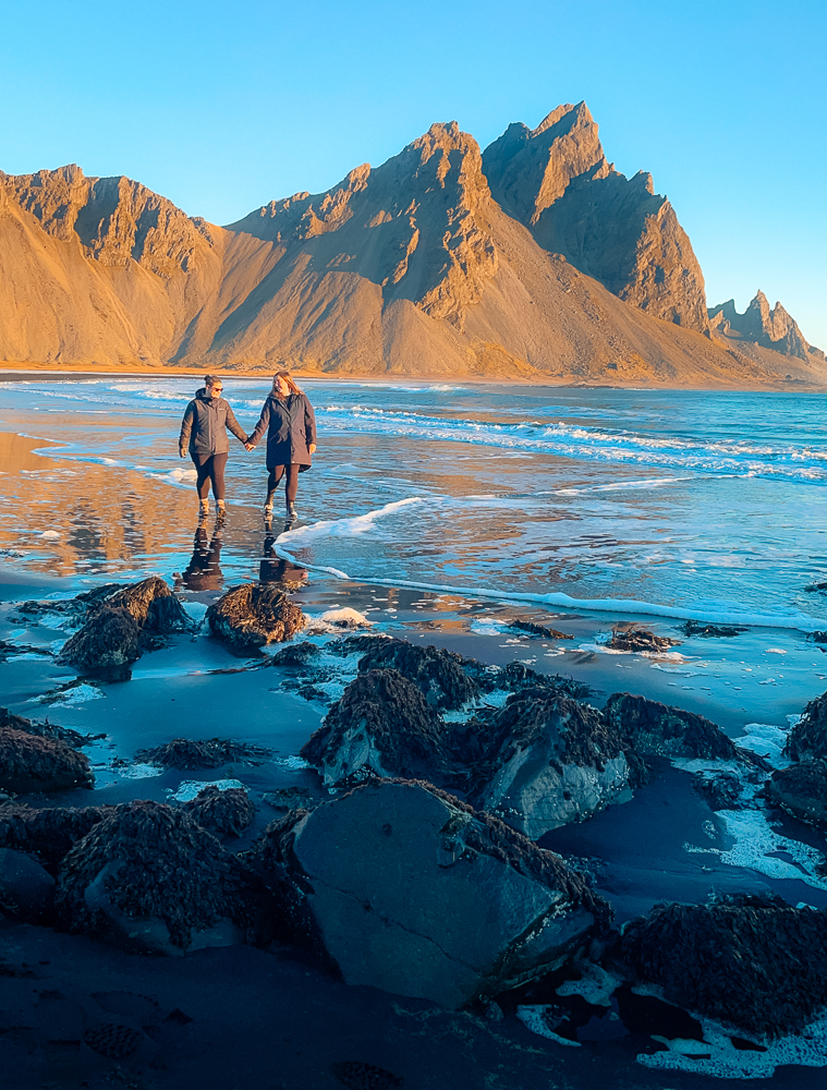 Couple walking on Stokksnes Beach at sunrise on Iceland five day ring road itinerary
