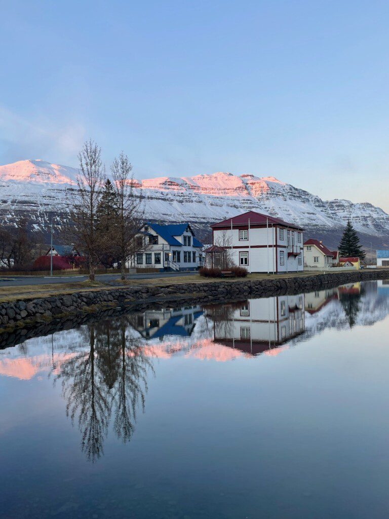 Snowy mountains and village reflecting in lake at Seydisfjordur Iceland