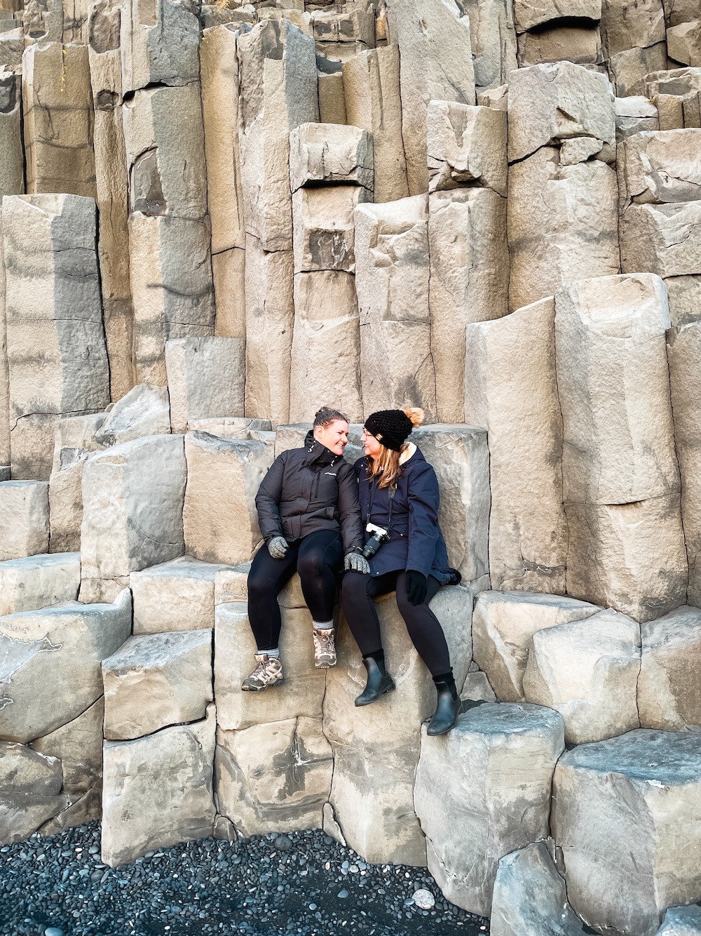Couple sitting on basalt columns at Reynisfjara Black Sand Beach